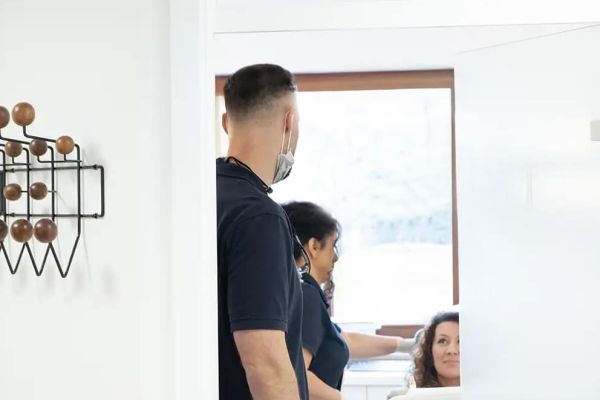 Ein Zahnarzt kommt in das Behandlungszimmer wo eine Patientin wartet