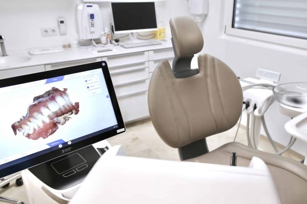 Behandlungszimmer mit Bildschirm auf dem ein digitaler Scan eines Gebisses zu sehen ist