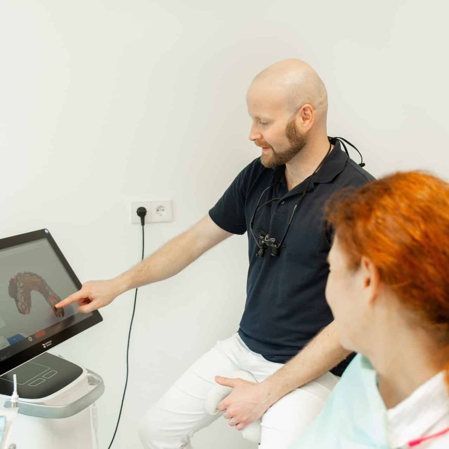 Zahnarzt Dr. Klein schaut mit Patientin digitale Ergebnisse des 3D-Scans an