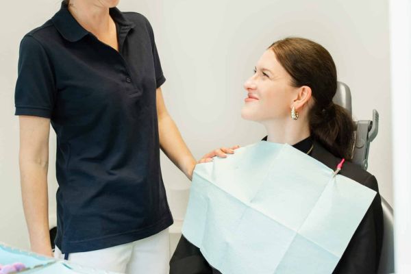 Eine Zahnarzthelferin lächelnd mit Patientin