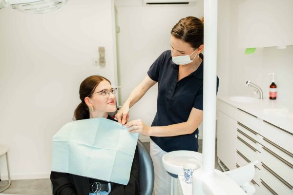 Eine freundliche und hilfsbereite Zahnarzthelferin mit einer Patientin im Behandlungszimmer