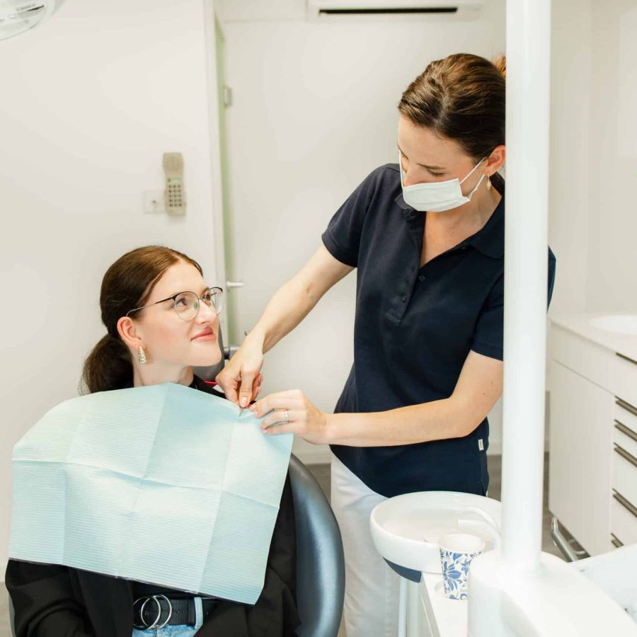 Eine freundliche und hilfsbereite Zahnarzthelferin mit einer Patientin im Behandlungszimmer