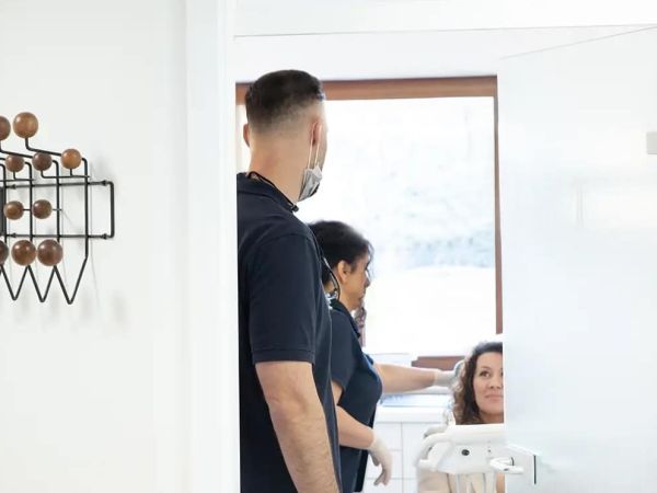 Ein Zahnarzt kommt in das Behandlungszimmer wo eine Patientin wartet