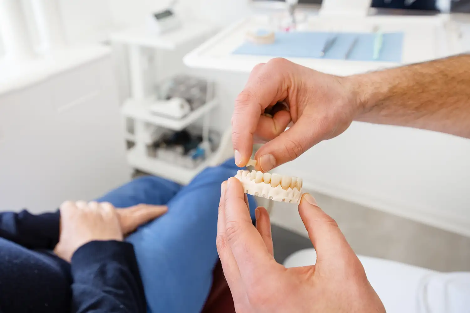 Ein Zahnarzt von Zahnkonform hält ein Zahnmodell in der Hand und erklärt es einem Patienten